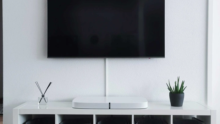 En TV-skjerm henger på veggen, med en TV-benk under seg.