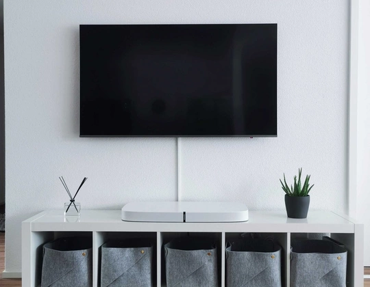 En TV-skjerm henger på veggen, med en TV-benk under seg.